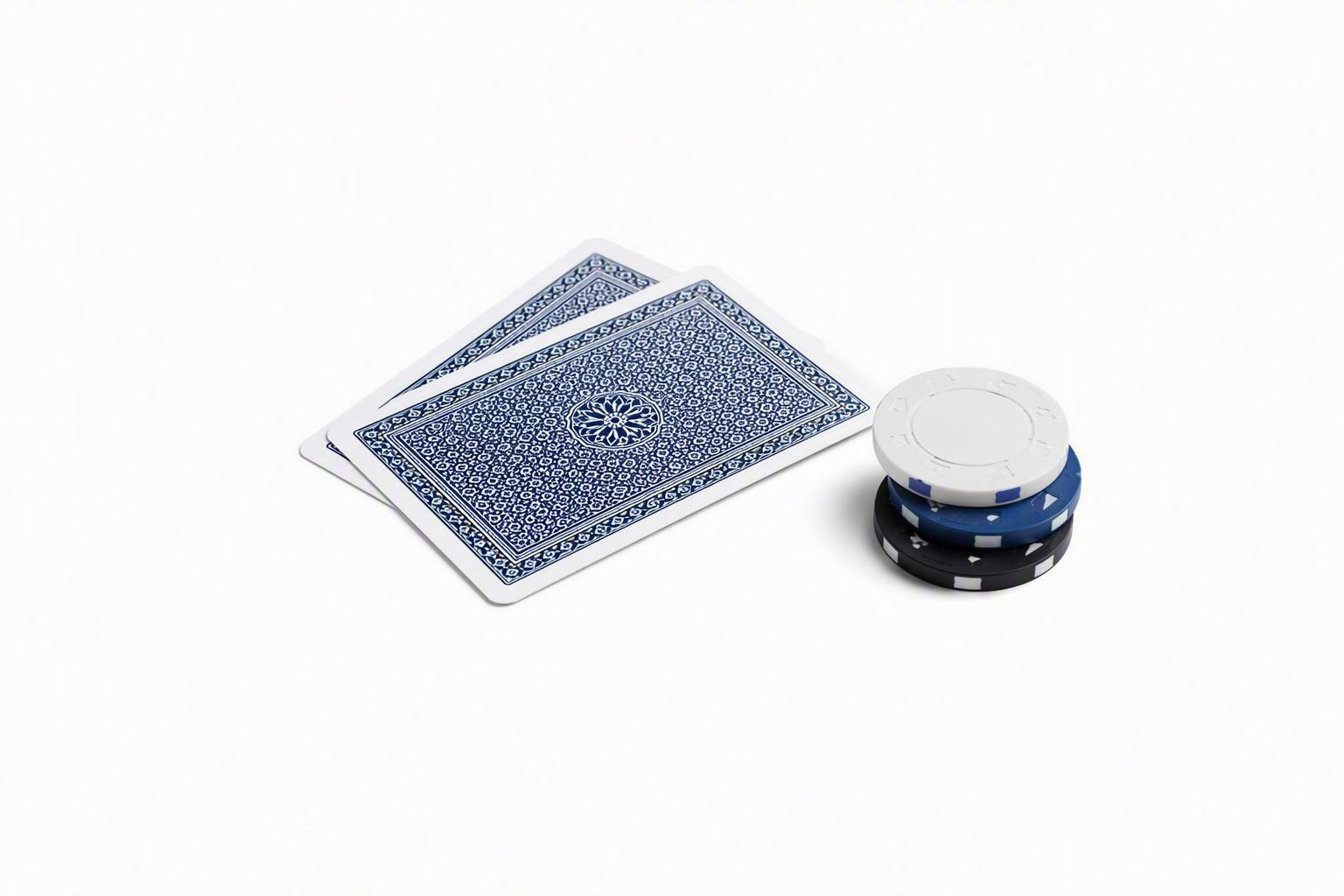 Two face-down playing cards and casino chips on a white table
